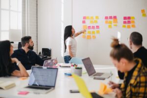 Woman placing sticky notes on wall of business meeting.